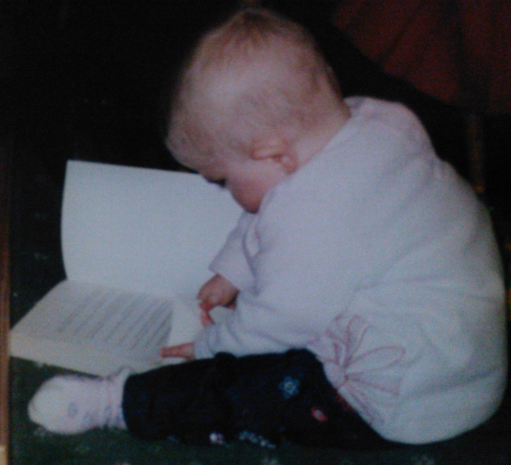 Baby Laura reading a grown-up book, aged less than 1