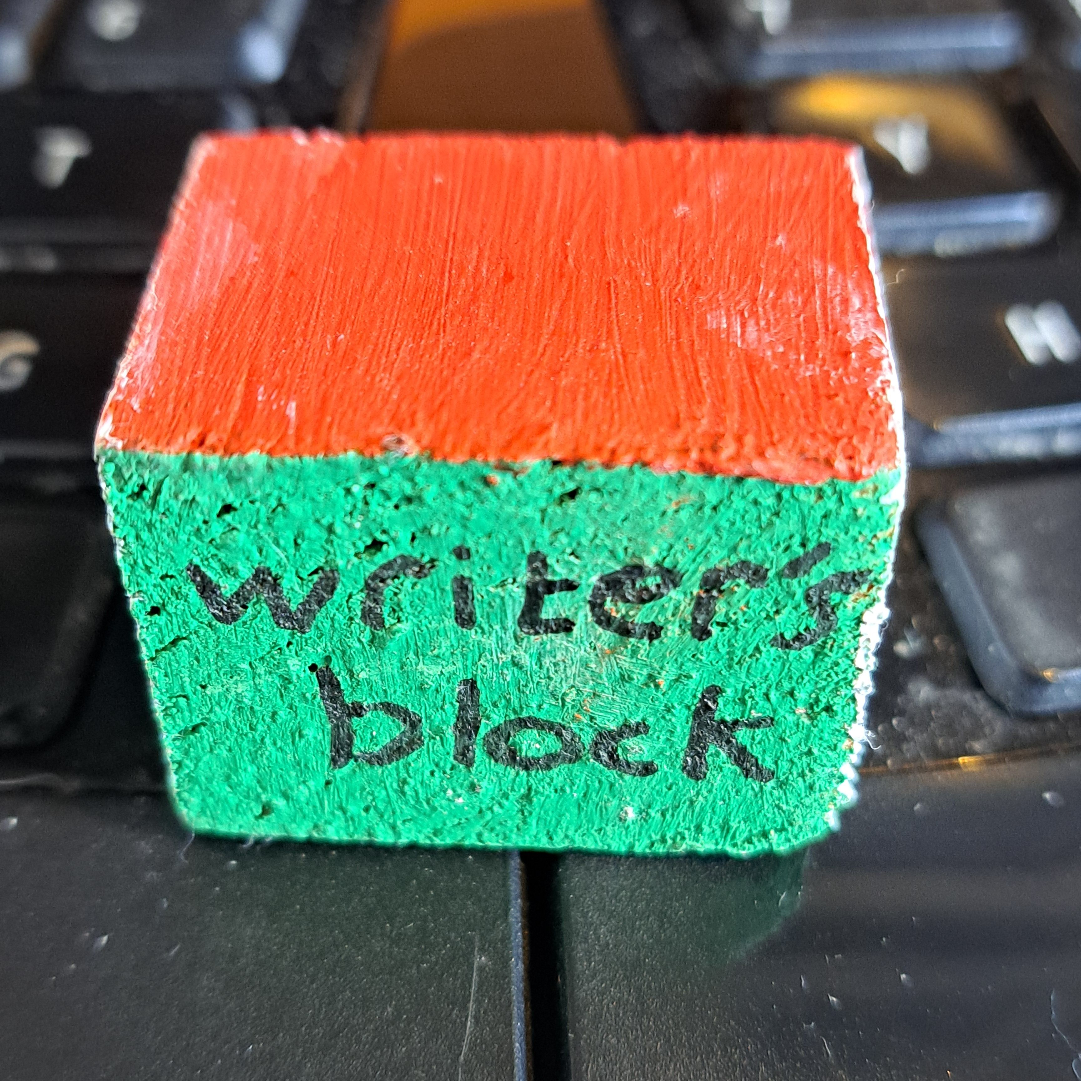 wooden cube with writer's block painted on one side